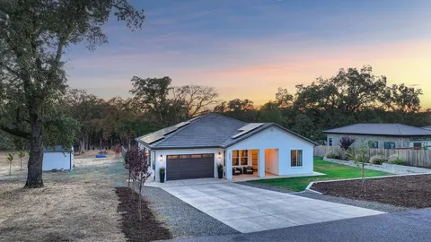 a front view of a house with yard and tree