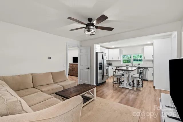 a living room with furniture and a flat screen tv with kitchen view
