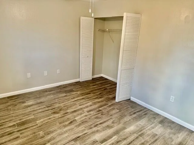 a view of an empty room with wooden floor and a ceiling fan
