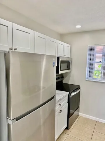 a kitchen with stainless steel appliances granite countertop a refrigerator a stove a sink and a microwave