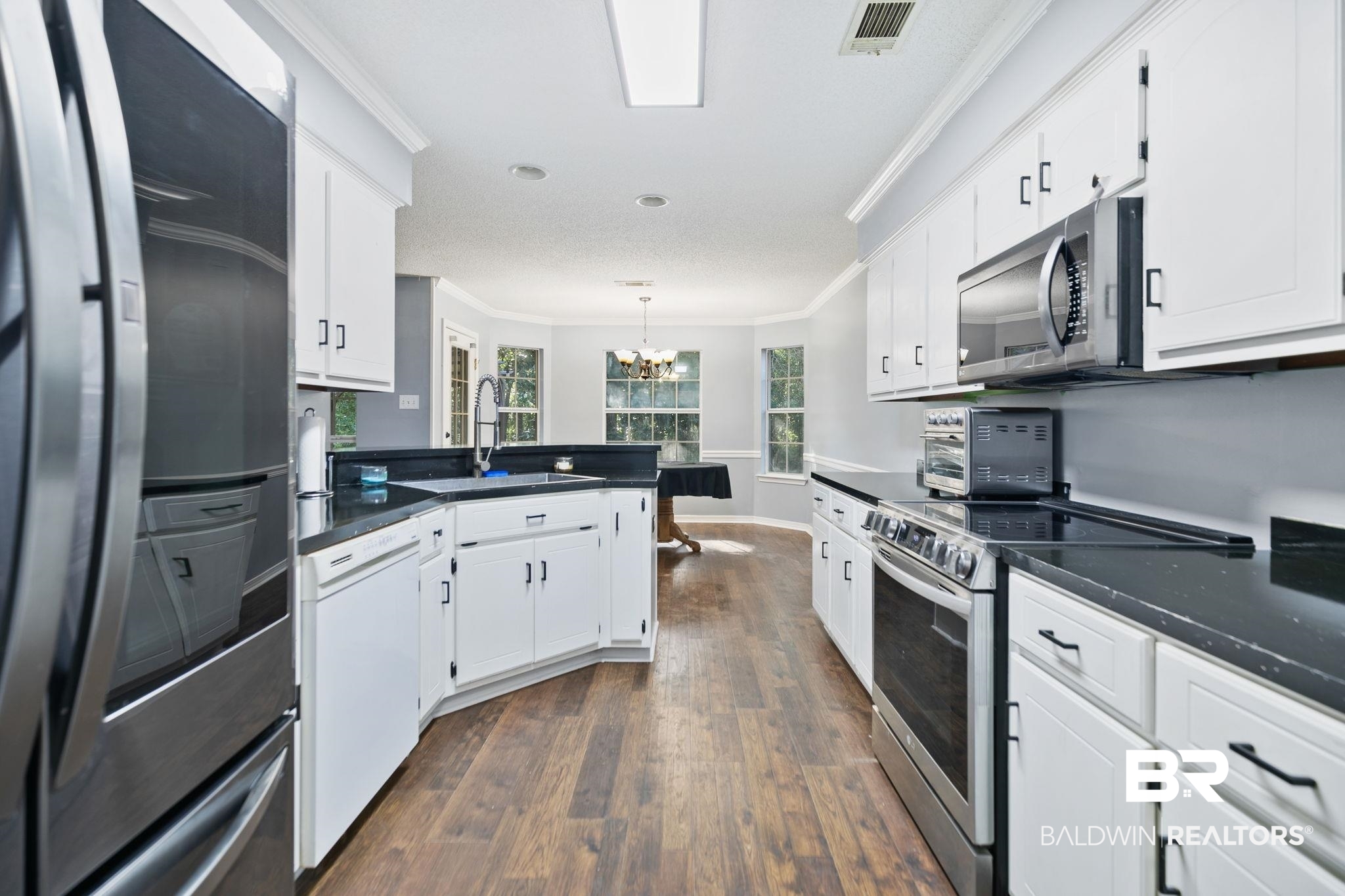 10550 Patrick Avenue Grand Bay, AL 36541 - Photo 19 of 43 Kitchen featuring white cabinetry, a chandelier, dark hardwood / wood-style flooring, crown molding, and appliances with stainless steel finishes