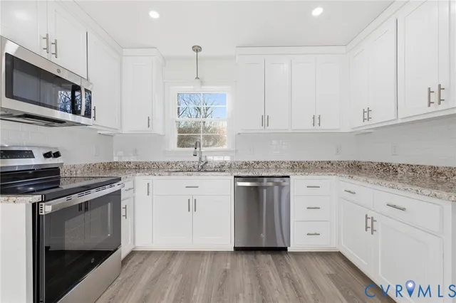 a kitchen with stainless steel appliances granite countertop a stove a sink and white cabinets