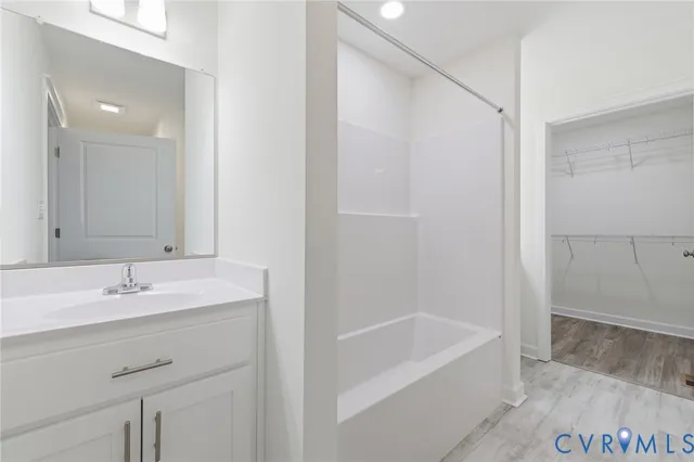 a bathroom with a tub sink vanity and a mirror