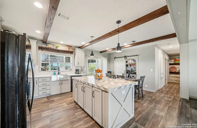 a kitchen that has a lot of cabinets in it and wooden floors