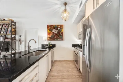 a kitchen with stainless steel appliances granite countertop a sink and a refrigerator