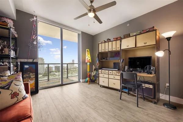 a living room with furniture a flat screen tv and a floor to ceiling window