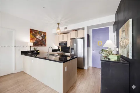 a kitchen with stainless steel appliances a sink a stove a refrigerator cabinets and a dining table