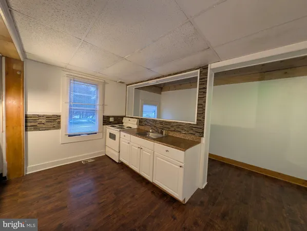 a large kitchen with wooden floor and stainless steel appliances