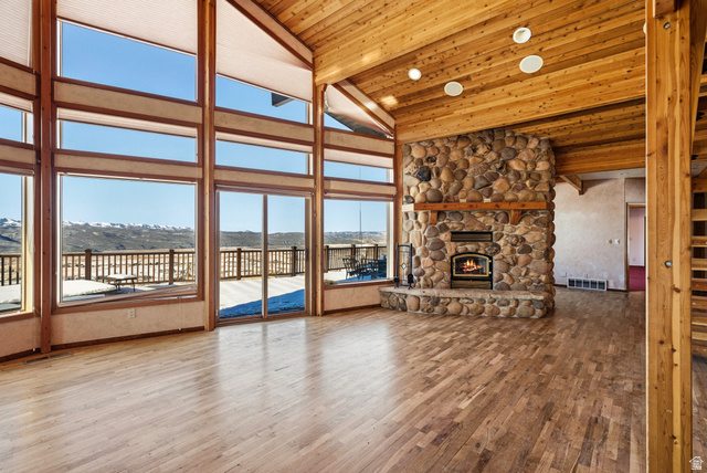 3090 North Rocky Road Kamas, UT 84036 - Photo 3 of 17 Unfurnished living room featuring a stone fireplace, high vaulted ceiling, wood-type flooring, a mountain view, and a wood ceiling with exposed beams