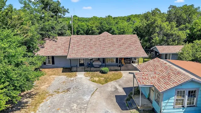 an aerial view of a house with swimming pool and large trees