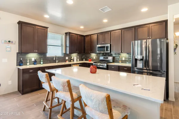 a kitchen with stainless steel appliances granite countertop a refrigerator a stove a sink a dining table and chairs