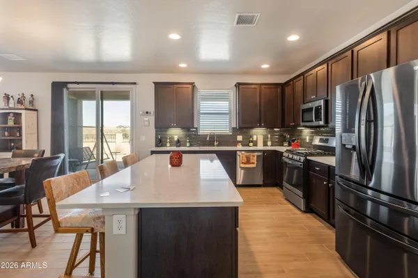 a kitchen with stainless steel appliances granite countertop a refrigerator a stove top oven a sink dishwasher and white cabinets with wooden floor