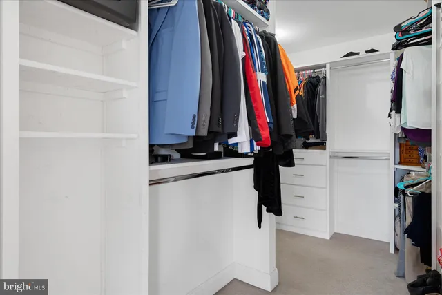 a view of walk in closet with clothes and shoes