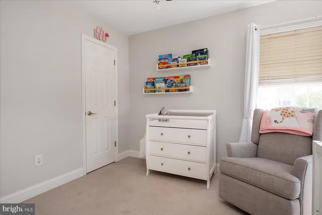 a room with a baby bed couch and a window