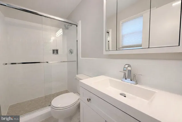 a bathroom with a toilet a sink a mirror a vanity and shower