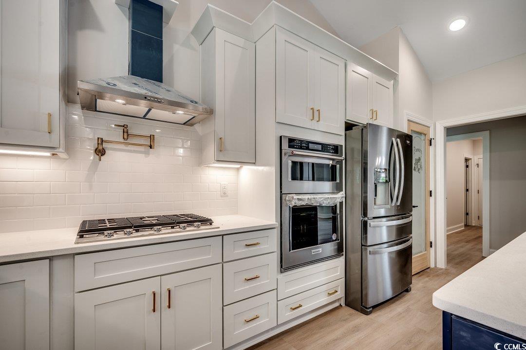 1007 Brood Court Conway, SC 29526 - Photo 12 of 40 Kitchen with wall chimney range hood, stainless steel appliances, light wood-type flooring, and light countertops