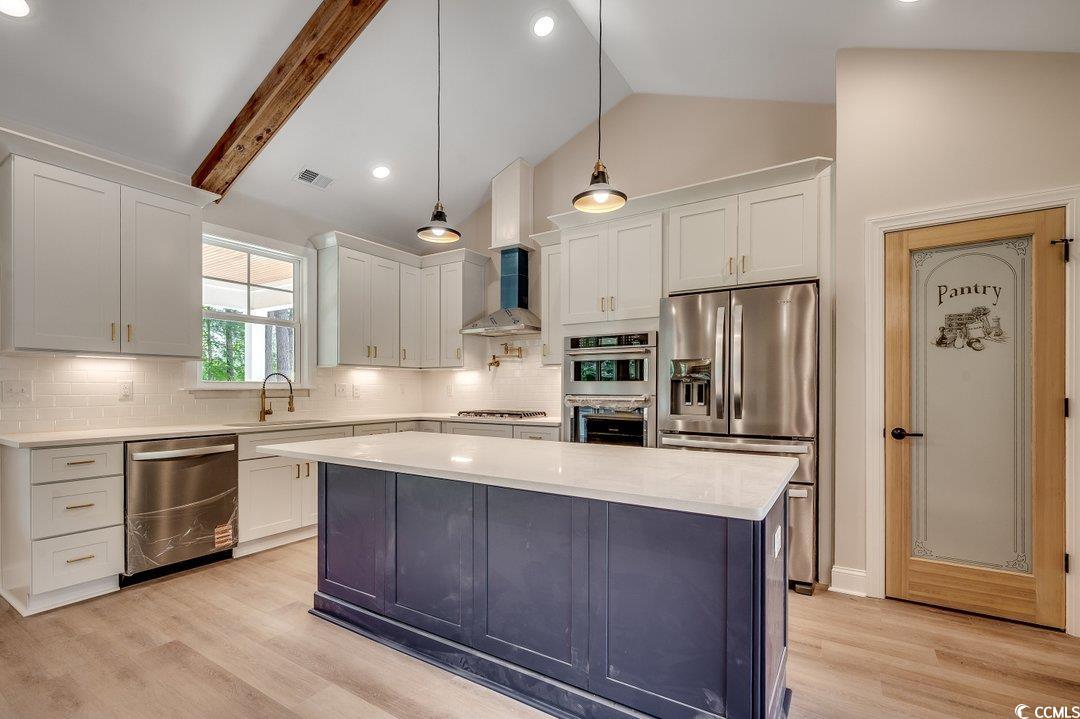 1007 Brood Court Conway, SC 29526 - Photo 10 of 40 Kitchen with stainless steel appliances, light countertops, visible vents, vaulted ceiling with beams, and wall chimney exhaust hood