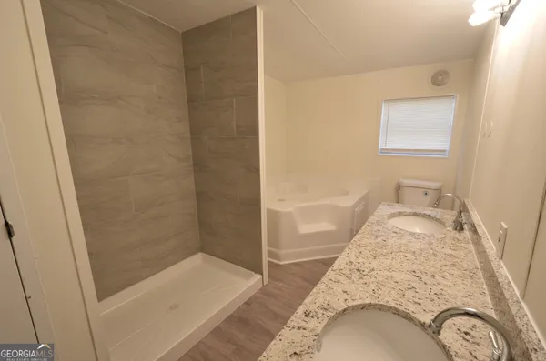 a bathroom with a granite countertop sink a mirror and shower