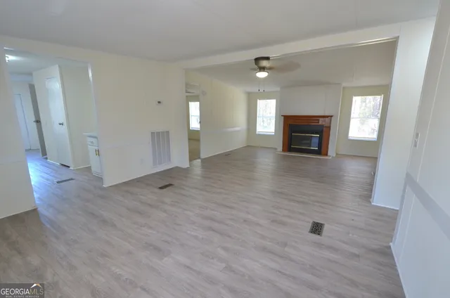 a view of an empty room with wooden floor and a fireplace