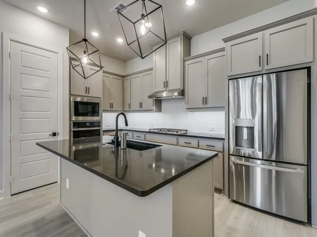 a kitchen with stainless steel appliances granite countertop a refrigerator a sink and a stove
