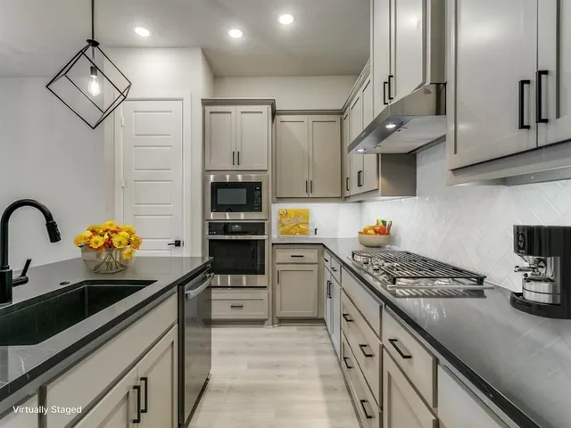 a kitchen with stainless steel appliances granite countertop a refrigerator a stove and a sink with cabinets
