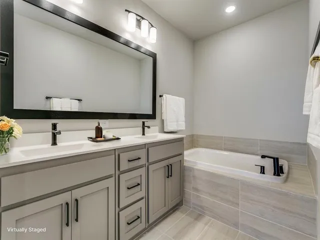 a bathroom with a tub sink and mirror