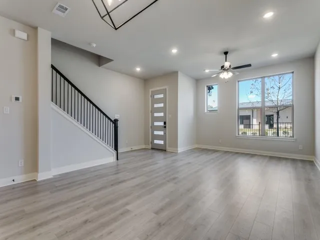 an empty room with wooden floor chandelier and windows