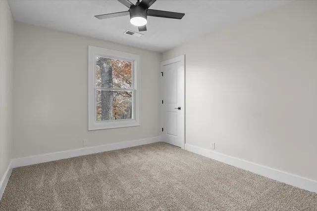 an empty room with a window and a fan