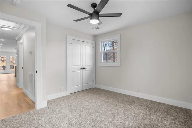 an empty room with windows and a ceiling fan