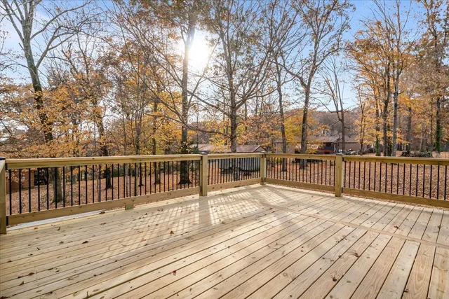 a view of a deck with wooden floor and fence with a large tree