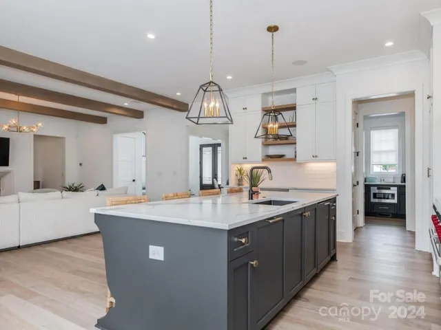 a large kitchen with kitchen island a sink stainless steel appliances and a chandelier
