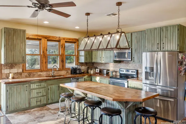 a kitchen with stainless steel appliances granite countertop a sink a stove and chairs