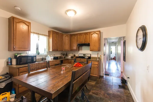 a large kitchen with a table chairs wooden cabinets and stainless steel appliances