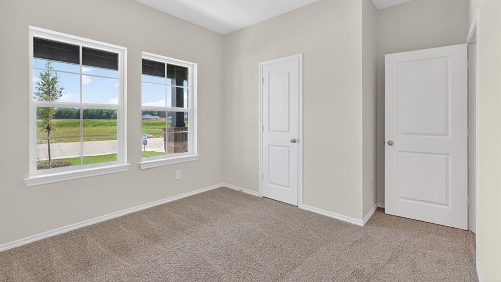 4008 Ripplewood Drive Lindale, TX 75771 - Photo 7 of 37 Carpeted room with light neutral wall paint, two paneled doors, and two double-hung windows with white trim