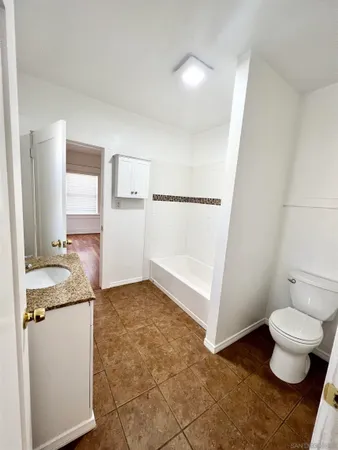 a bathroom with a granite countertop sink a toilet and a mirror