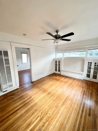 a view of empty room with wooden floor and fan