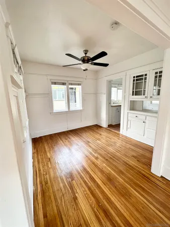 a view of empty room with wooden floor and fan