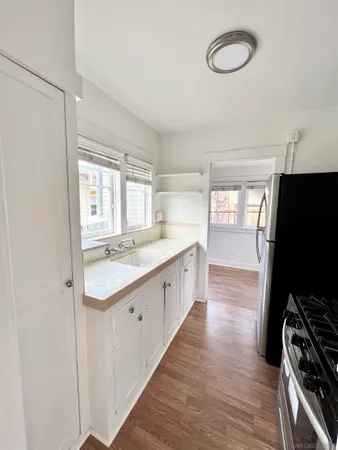 a large kitchen with a sink and wooden floor