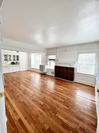 a view of empty room with wooden floor and fireplace