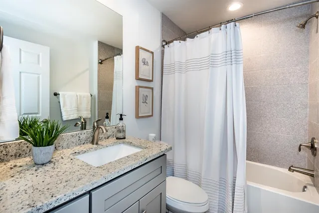 a bathroom with a granite countertop sink a toilet and shower