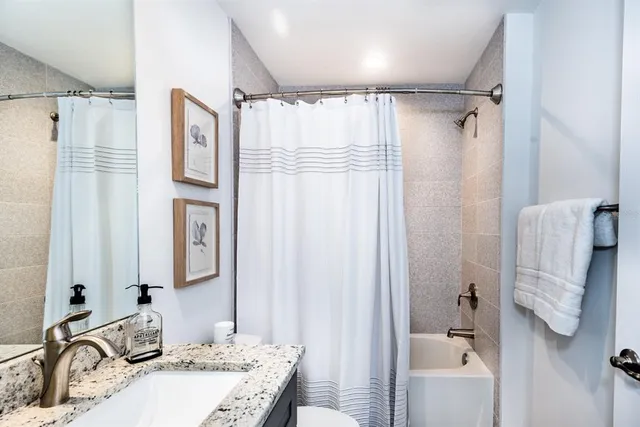 a bathroom with a granite countertop sink vanity mirror and shower