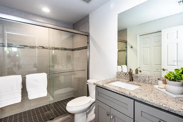 a bathroom with a granite countertop sink toilet and shower