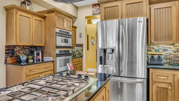 a kitchen with stainless steel appliances granite countertop a refrigerator and a stove top oven