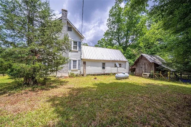 a view of a house with a yard and large tree