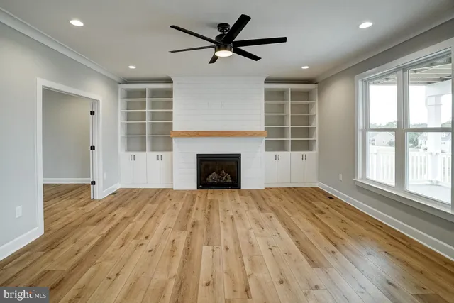 a kitchen with stainless steel appliances kitchen island granite countertop a stove a sink dishwasher a refrigerator and white cabinets with wooden floor