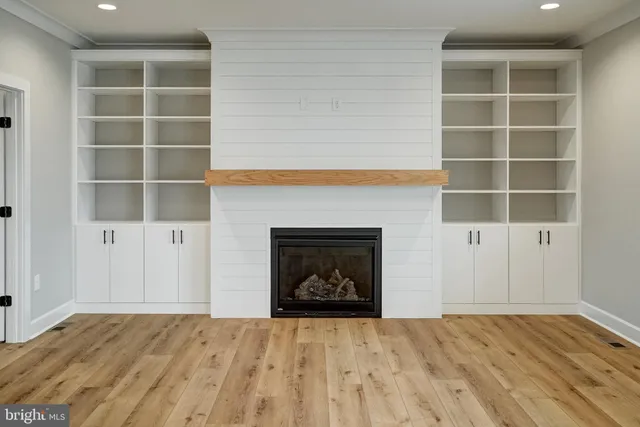 a large kitchen with stainless steel appliances a sink a stove a refrigerator and island with wooden floor