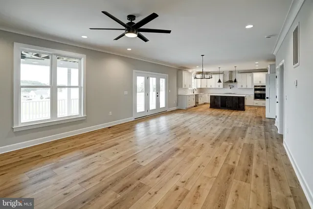 a large kitchen with stainless steel appliances a large counter top a stove and a sink with wooden floor