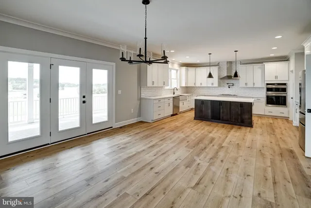 a large kitchen with granite countertop a stove a sink a refrigerator and white cabinets