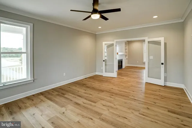 a view of an empty room with window and wooden floor