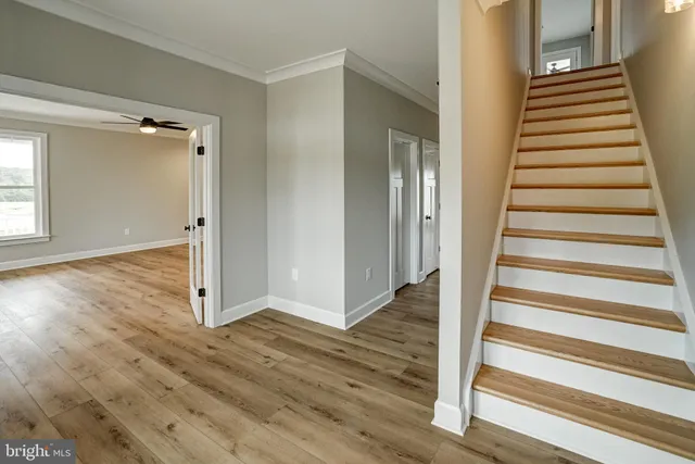 a view of empty room with wooden floor and fan